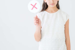 バツ印を掲げる女性
